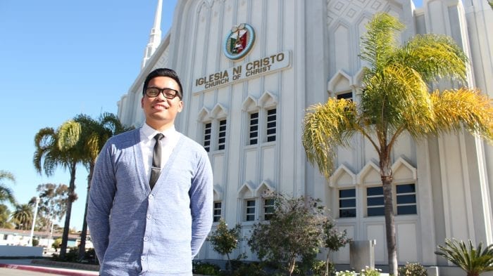 man smiling and standing in front of worship building