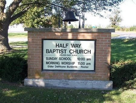 A park setting with brick wall signage that reads Half Way Baptist
Church