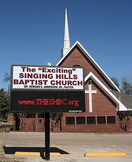 A sign in front of a chapel that says The “Exciting” Singing Hills Baptist
Church