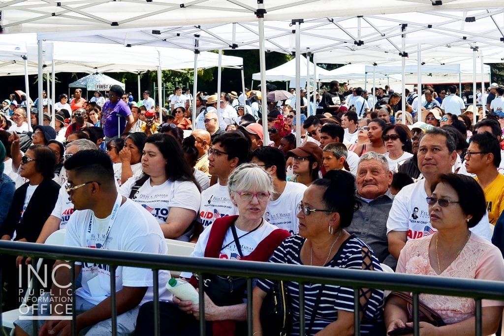 Hundreds of Oakland residents sitting in the shade enjoying the Aid to Humanity event.
