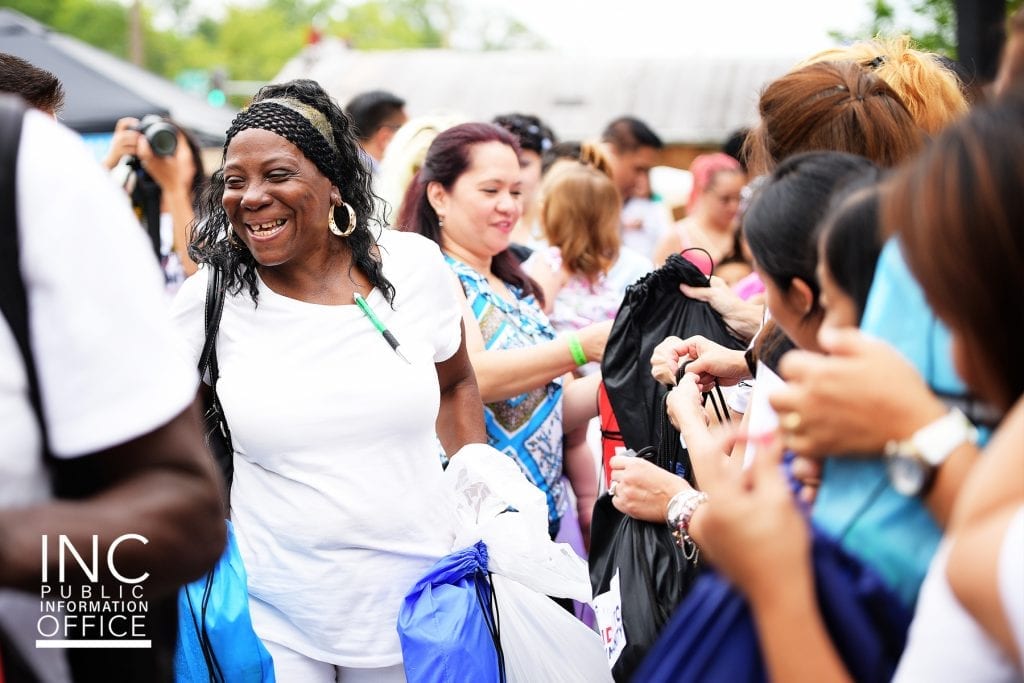 Smiling woman accepting backpack of school supplies