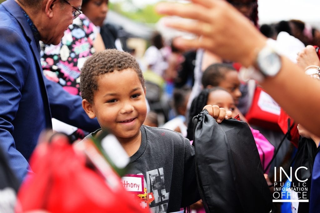 Smiling young boy accepting backpack of school supplies