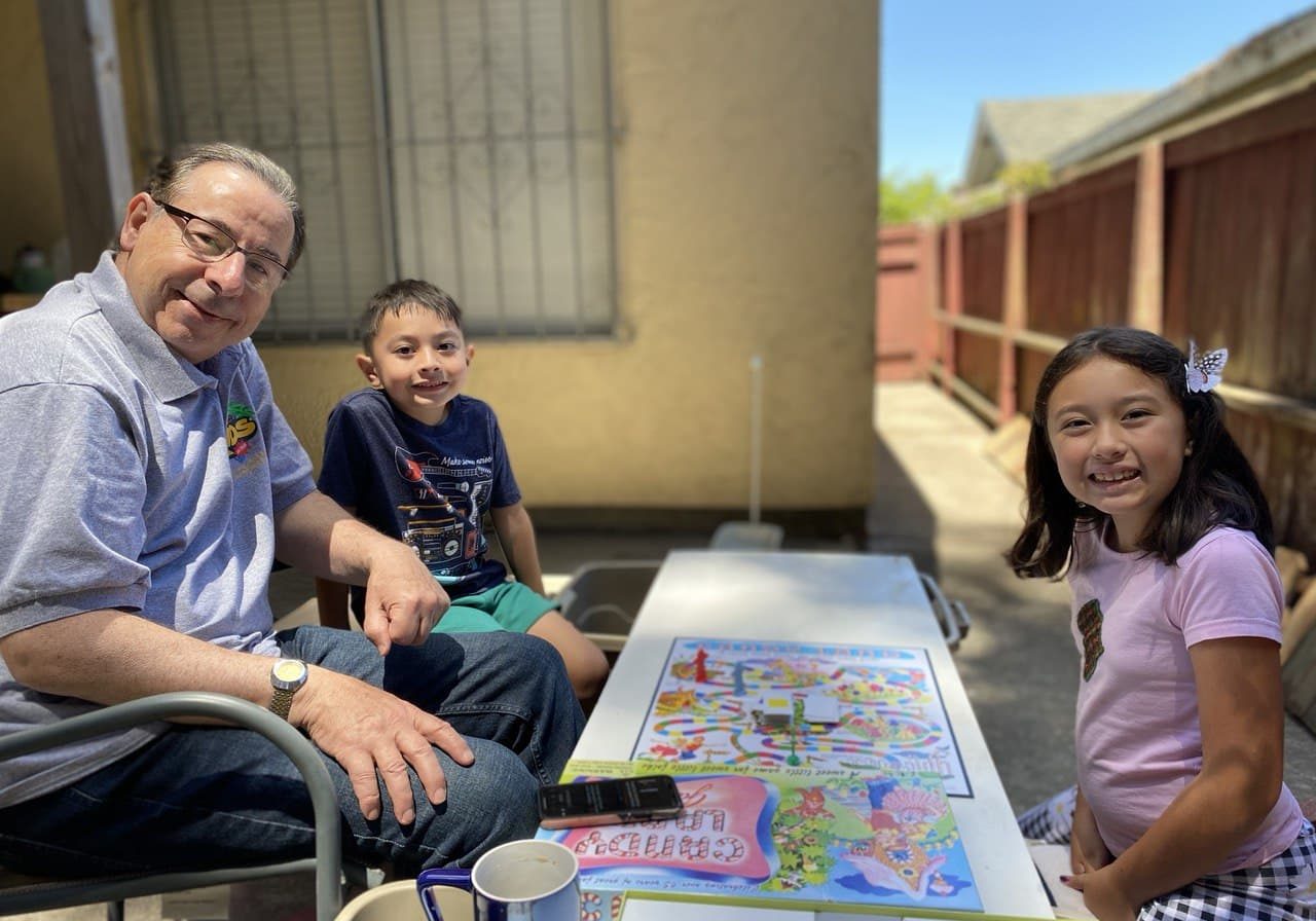 grandad smiling with grandkids with board games on the table