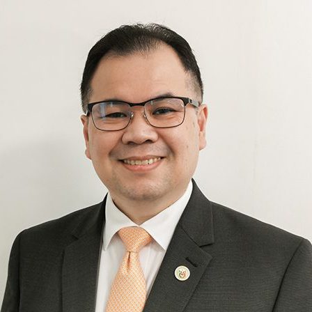 minister wearing suit with orange tie, with white background